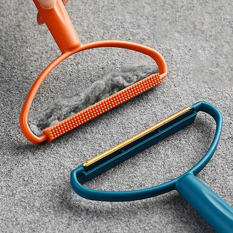 Two pet grooming tools, one orange and one blue, on a textured surface.