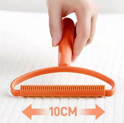 Orange pet grooming brush with a hand holding it, on a white background.